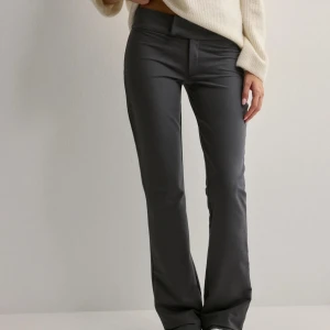 Grå kostymbyxor  - Snygga grå kostymbyxor med bootcut-stil och låg midja. Dem är ifrån Nelly och i storlek 38.använda fåtal gånger, inga defekter. Säljer pågrund av att jag valde fel storlek men orkade inte skicka tillbaka dem så jag har använt dem lite.