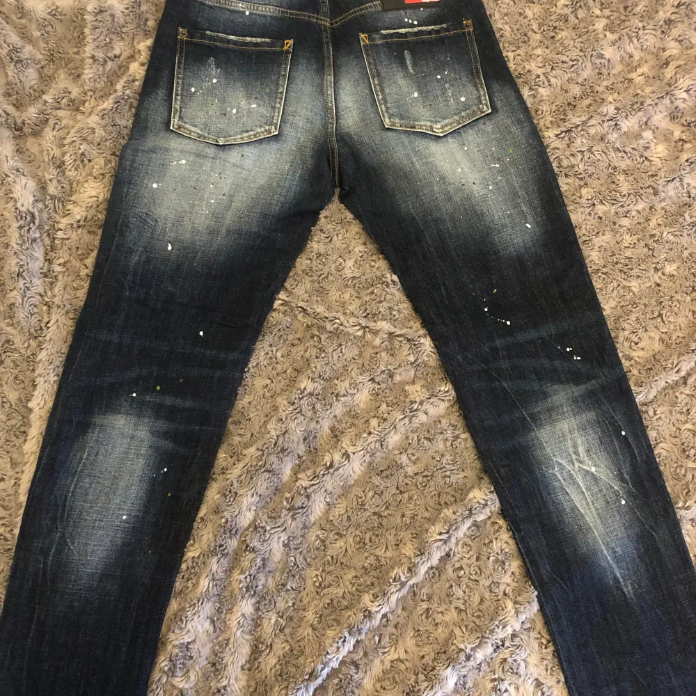 Snygga mörkblå jeans från Dsq2 med slitningar och färgstänk. W30-L32, aldrig använda. Öppen för prisförslag vid snabb och smidig affär . Farkut & Housut.