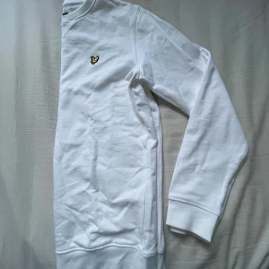 Vit sweatshirt från Lyle & Scott - Säljer en stilren vit sweatshirt från Lyle & Scott med deras ikoniska logga på bröstet. Tröjan har långa ärmar och en klassisk passform. Perfekt för en avslappnad look. Storlek 170 men passar XS eller S