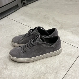 Äkta! Gråa Lindeberg skor i mocha - Snygga grå sneakers i mocka med snörning och vit sula. Perfekta för en stilren look.