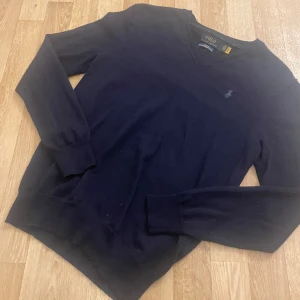 Merinoull tröja från Polo Ralph Lauren - Säljer en stilren mörkblå tröja från Polo Ralph Lauren i merinoull. Tröjan har en slim fit passform och långa ärmar. Perfekt för en elegant och bekväm look.