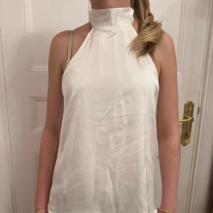 Vit halterneck-top - Snygg vit halterneck-top med hög krage och knytning i nacken. Perfekt för en middag. Aldrig använd