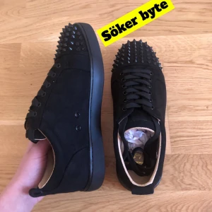 Söker byte  - Söker byte för dessa snygga svarta sneakers med nitar på tån. Skorna har en röd sula och snörning framtill. Perfekta för att ge en edgy touch till din outfit.