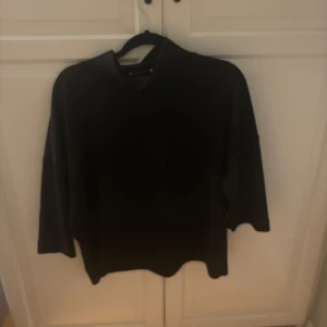 Svart tröja från Carin Wester - Snygg svart tröja från Carin Wester i storlek S. Tröjan har en enkel och stilren design med halvkort ärmar och en rund halsringning. Perfekt för en minimalistisk look. Väldigt stil ren