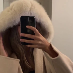 Beige garoff kappa  - PRIS GÅR ATT DISKUTERA!! Elegant beige garoff kappa med stor luva med mjuk päls. Kappan har ett knytbälte i midjan och långa ärmar. Den användes under hösten förra året men har absolut inga fel, smuts eller liknande. Säljs för ett  mycket billigare pris än på hemsidan🥰