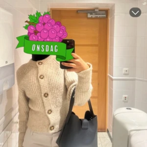 Beige ribbad kofta med knappar - Säljer en stilren beige kofta med ribbad struktur och stora knappar framtill. Perfekt för kyligare dagar och lätt att matcha med olika outfits.