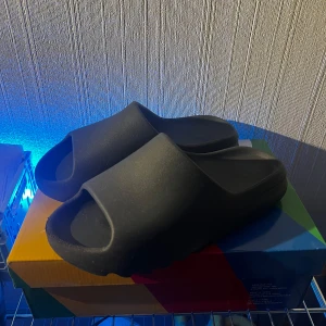 Svarta sandaler - Säljer ett par svarta yeezy slides. I bra skick men liten sliten där framme. 