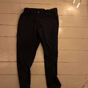 Golf byxor puma - Snygga svarta byxor från Puma med en klassisk design. Byxorna har en knapp och dragkedja framtill samt en diskret logga på baksidan. Perfekta för en stilren look.den är i barn storlek 