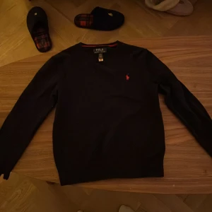 Svart tröja från Polo Ralph Lauren - Snygg svart tröja från Polo Ralph Lauren med röd logga på bröstet. Tröjan har långa ärmar och en klassisk passform. Perfekt för en stilren look.i barn storlek 