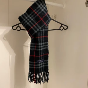 Burberry - Säljer nu denna Snygga halsduk från Burberry i blått. Tillverkad i 100% mjuk kashmir med klassiskt fransad kant. Perfekt för att hålla dig varm och stilren under kyliga dagar. Hör av er vid funderingar☺️