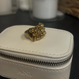 Edblad ring - Snygg guldfärgad ring dekorerad med flera små nitar i ett geometriskt mönster. Perfekt för att ge en edgy touch till din outfit. Passar både till vardag och speciella tillfällen.