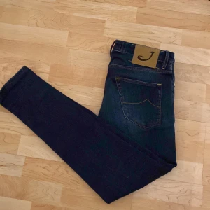 Mörkblå jeans från Jacob Cohen - Snygga mörkblå jeans från Jacob Cohen med klassisk femficksdesign och gulddetaljer. Jeansen har en normal passform och är tillverkade i högkvalitativt denim. Perfekta för en stilren look. Priset kan vara förhandlingsbart 