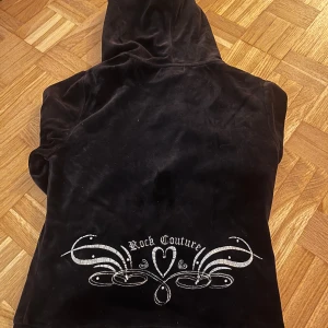 Svart hoodie från Wet Seal - Snygg svart hoodie från Wet Seal med dragkedja och huva. Den har ett tryck med texten 'Rock Couture' och dekorativa detaljer i silver på baksidan.  Står att det är storlek medium men passar S-M! 💗💗