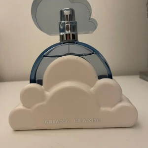 Parfymflaska från Ariana Grande - Jag säljer min Cloud parfym från Ariana Grande eftersom att den inte kommer till så mycket användning. Parfymen är en 100 ml flaska och har används några gånger men det finns trots det mycket parfym kvar i flaskan. 