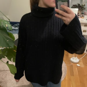 Svart polotröja från H&M - Mysig svart polotröja från H&M med ribbad struktur. Perfekt för kyliga dagar med sin höga krage och långa ärmar. En klassisk och stilren tröja som passar till det mesta.