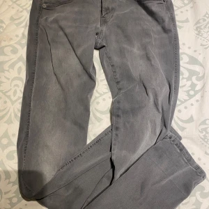 Grå jeans från Replay - Snygga grå jeans från Replay i modellen Anbass. De har en klassisk femficksdesign och en bekväm passform. Perfekta för en stilren look.