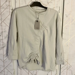 Beige långärmad tröja från Zara - Nyköpt beige långärmad tröja från Zara Girls. Tröjan har en unik rynkad detalj framtill. Den är tillverkad i ett mjukt material som känns skönt mot huden. artikelnummer 4805/600/805. Slutsåld