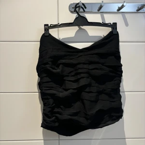 Svart tubtopp från Bik Bok - Snygg svart tubtopp från Bik Bok med rynkade detaljer och elastisk baksida för en bekväm passform. Perfekt för en stilren look.