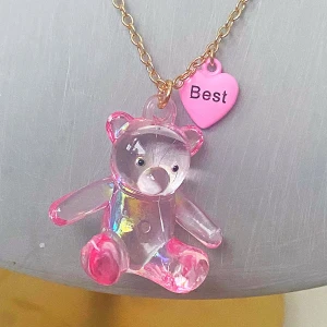 Gulligt halsband med nalle och hjärta - Charmigt halsband med en genomskinlig rosa nalle och ett rosa hjärthänge med texten 'Best'. Kedjan är i guldton och justerbar i längd. Perfekt för att ge en söt touch till din stil.