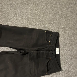 Svarta jeansbyxor - Snygga svarta jeansbyxor med klassisk design och knappar framtill. Perfekta för en stilren look.