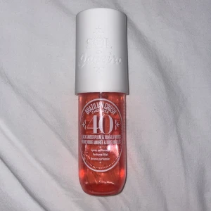 Sol de Janeiro Brazilian Crush Cheirosa 40 - Upptäck Sol de Janeiro Brazilian Crush Cheirosa 40, en doftspray med noter av svart bärnsten och vaniljträ. Flaskan är stilrent designad med en vit kork och en genomskinlig orange flaska som ger en fräsch och exotisk känsla. Ca 1/4 kvar därav pris 🍓🍦