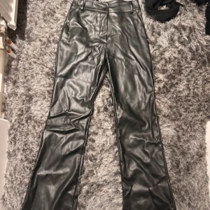 Svarta skinnbyxor från MadLady - Snygga svarta skinnbyxor från MadLady i storlek S. Byxorna har en högmidjad passform och stängs med knapp och dragkedja.