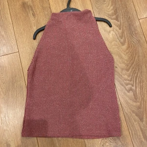 Röd ribbad halterneck topp - Snygg röd ribbad halterneck topp med en stilren design. Perfekt för att lägga till en touch av färg till din garderob. Passar bra till både jeans och kjol.