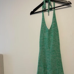Grön stickad klänning från Bik Bok - Säljer en superfin grön tajt stickad klänning från Bik Bok. Den är ärmlös och har en snygg halterneck-design som knyts i nacken. Perfekt för sommarens alla fester eller en avslappnad dag på stan. Klänningen är i storlek S och har en härlig, mjuk känsla. 
