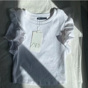 Zara Topp - Säljer min vita zara topp med volanger för att den inte kommer till användning💗Väldigt söt och i fint skick, sparsamt använd💕Storlek M men den sitter som S (Lånade bilder)