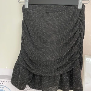 Tajt glittrig kjol med volanger  - Svart glittrig kjol köpt från kappahl! Så så fin och i utmärkt skick! Säljer på grund av att jag inte använder längre. Skriv för bilder och frågor💕