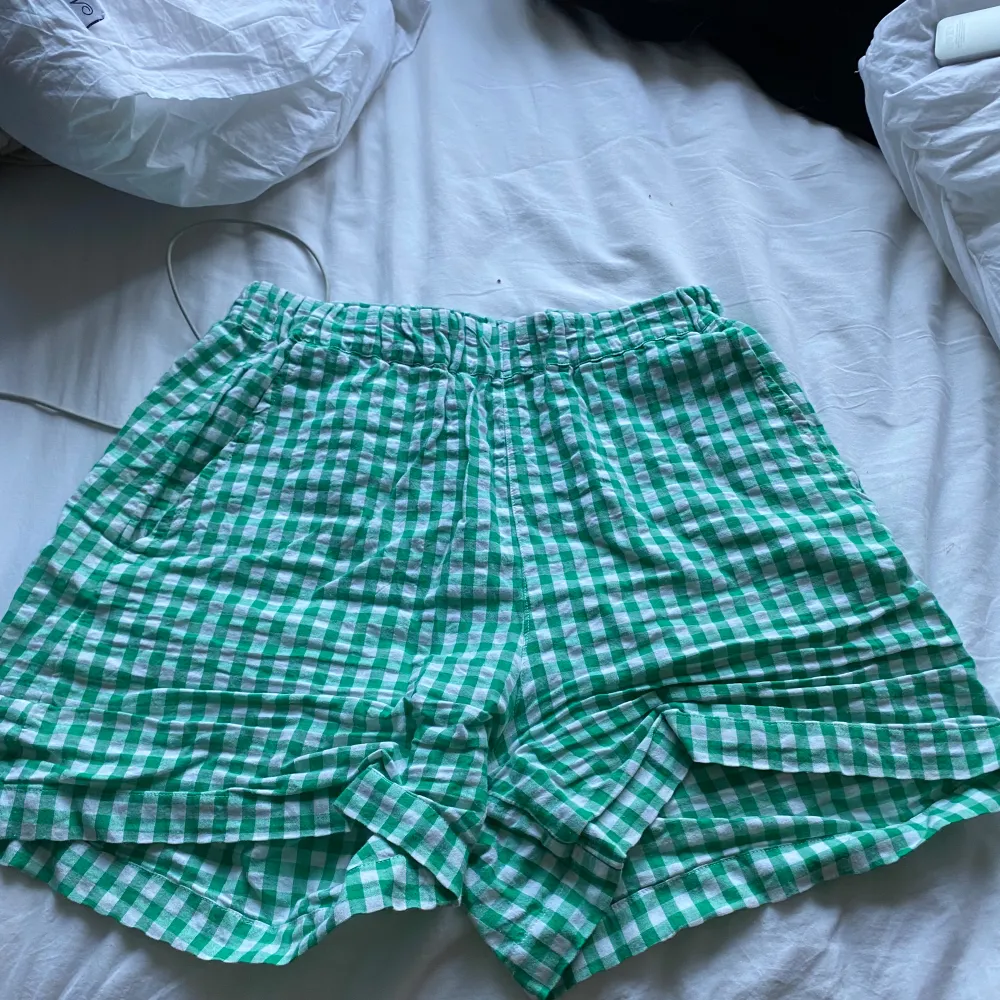 Säljer ett par supercharmiga gröna och vita rutiga shorts från Lindex. De är i storlek XS och har en bekväm elastisk midja. Perfekta för sommardagar eller en avslappnad vårlook. Materialet känns lätt och luftigt, vilket gör dem idealiska för varma dagar. 🟢. Shorts.