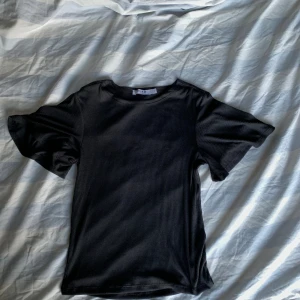 Svart ribbad topp från NA-KD - Säljer en svart ribbad topp från NA-KD i storlek S. ärmarna är lite utsvängda! 