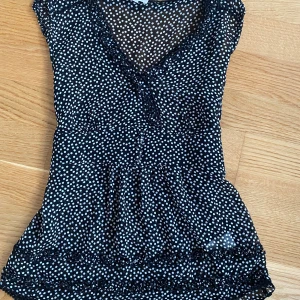 Svart prickig blus från Stockh LM - Säljer en superfin svart blus med vita prickar från Stockh LM. Den har en v-ringad design och volangdetaljer vid rigningen som ger en söt detalj. 