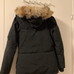 Svart parkajacka med pälsdetalj - Säljer en snygg svart parkajacka med en mysig päls. Perfekt för kalla vinterdagar! Jackan har långa ärmar och en klassisk passform. Den är i bra skick och redo för nya ägare. Den ligger just nu och tar en massa plats. Modellen heter Montebello. Jag går ner vid snabbaffärer och köparen står för frakten🌸