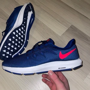 Nike running skor  - Säljer ett par snygga blå Nike löparskor i mycket bra skick. De har en rosa/röd Nike-logga på sidan och en vit sula med bra grepp. Perfekta för träning och löpning. Skorna har snörning och är gjorda i ett lätt syntetmaterial som andas. Som sagt i mycket bra skick, inga slitningar eller smuts. Använts sparsamt fåtal gånger!