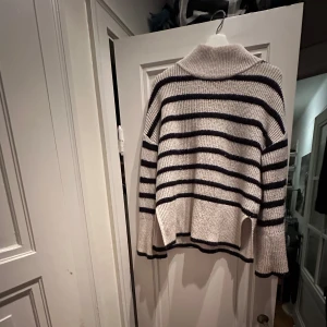 Randig stickad tröja med polokrage - Mysig stickad tröja. Den har högre krage och perfekt för kyliga dagar. Tröjan är i använt men bra skick och passar både höst och vinter. .