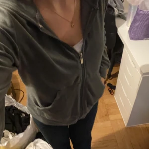 Grå hoodie med dragkedja - Mysig grå hoodie i mjukt material med dragkedja framtill. Perfekt för en avslappnad stil eller mysiga dagar hemma. Den har långa ärmar och en bekväm passform. Fickor på sidorna för extra funktionalitet.