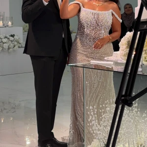 Elegant pärlbroderad förlovningsklänning - Säljer en fantastisk långklänning i ljus beige med vackra pärlbroderier. Klänningen har en tight passform och är perfekt för festliga tillfällen. Den är dekorerad med detaljer som ger en lyxig känsla.  Sydd för mina mått. Passar en 38a. Köpt för 10 000kr.