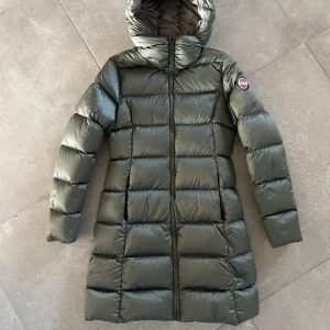 Grön dunjacka från Colmar - Säljer en snygg grön dunjacka från Colmar i mycket bra skick. Tyvärr har den en fläck längst ner, se bild 4 därav billigt pris. Jackan är lång och perfekt för kalla vinterdagar. Den har en praktisk huva och stängs med dragkedja. Storlek 14y - 166. Supermysig och håller dig varm hela säsongen! 💚 
