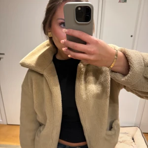 Beige teddyjacka - Mysig beige teddyjacka från NAKD i oversized stil. Perfekt för höst och vinter med sin fluffiga och varma design. Jackan har långa ärmar och en hög krage som skyddar mot kylan. Den är i mycket bra skick💕