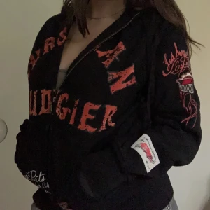 Svart hoodie från Christian Audigier - Säljer en svart hoodie från Christian Audigier med coola röda och vita tryck. Den har dragkedja fram och långa ärmar💗