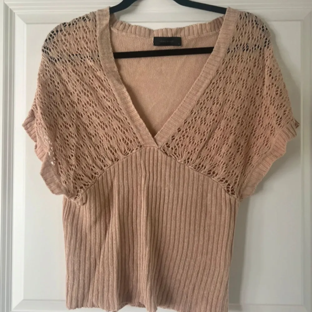 Säljer en superfin beige stickad topp från Vero Moda. Den har en v-ringad design med ett snyggt spetsmönster upptill och ribbad nederdel. . Tröjor & Koftor.