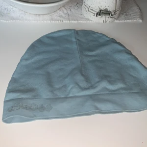 Ljusblå mössa från Slazenger - Säljer en ljusblå mössa från Slazenger i bra skick. Den är mjuk och bekväm, perfekt för kyliga dagar. Mössan har en diskret logga broderad på kanten. Passar både till vardags och sportiga aktiviteter. Perfekt för höst och vår!