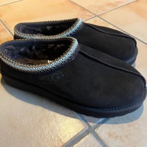 UGG tasman chocolate brown - nya - Tvärsköna ugg tasmans i choclate brown. Helt nya och oanvända, med prislapp kvar. De är fodrade med mjuk päls. Perfekta för att hålla fötterna varma inför vintern. Sulan är robust och ger bra grepp på golvet. Köpta i en skobutik i köpenhamn för 1099DDK, så drygt 1700kr (se bild 4). Självklart äkta. 