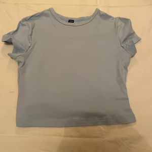 Ljusblå t-shirt från Shein - Säljer en enkel och stilren ljusblå t-shirt från Shein i storlek M. Perfekt för vardagsbruk med sin mjuka bomullskänsla och korta ärmar. Passar bra till både jeans och kjol för en avslappnad look.