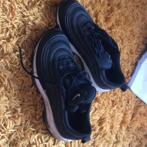Svarta Nike sneakers - Säljer ett par svarta Nike sneakers i bra skick. De har en snygg och sportig design med vita detaljer och klassisk snörning. Perfekta för både vardag och träning. Skorna är bekväma och ger bra stöd för fötterna.