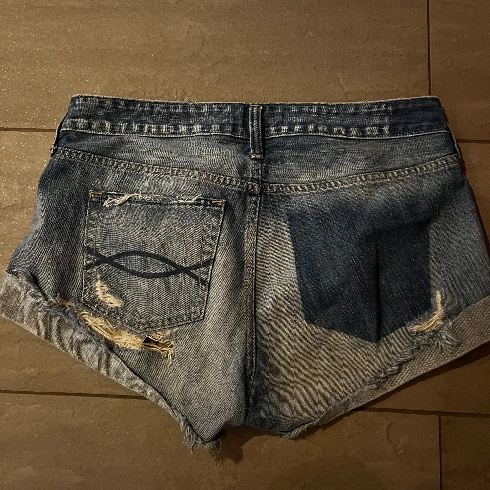 Säljer ett par coola blå jeansshorts med slitningar och råa kanter. Perfekta för en avslappnad sommarlook! De har en klassisk femficksdesign och är lågmidjade för en bekväm passform. Passar perfekt till en sommardag!🫶🏼❤️🩷midjemåttet tvärs över är 44cm🫶🏼. Shorts.