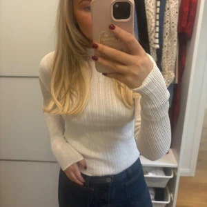 Vit ribbad polotröja - Säljer en superfin vit ribbad polotröja i mycket bra skick. Den är långärmad och har en tight passform som sitter snyggt på kroppen. Perfekt för både höst och vinter, och funkar lika bra till vardags som till fest. Tröjan är gjord i ett mjukt och bekvämt material. Passar perfekt till jeans eller kjol!