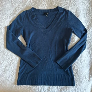 Blå v-ringad tröja - Säljer en snygg blå v-ringad tröja i bra skick. Den är långärmad och har ribbade muddar vid ärmslut och nederkant. 