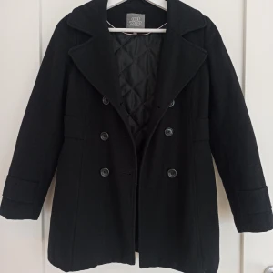 Svart kappa från Lindex - Säljer en stilren svart kappa från Lindex i storlek 152. Den har en klassisk dubbelknäppning och är quiltad på insidan för extra värme. Perfekt för höst och vinter! En knapp är ersatt, märks dock inte🌟 Brukar bära storlek XS, kort i ärmarna om man sträcker ut armarna, annars passar den bra💕